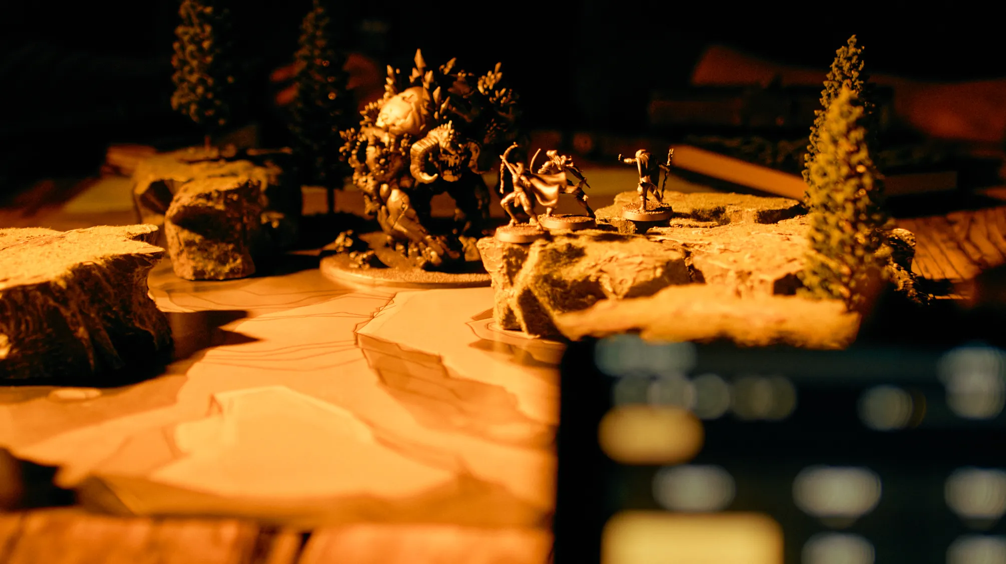 A still from the Bardio trailer: miniatures on a lit tabletop battle map